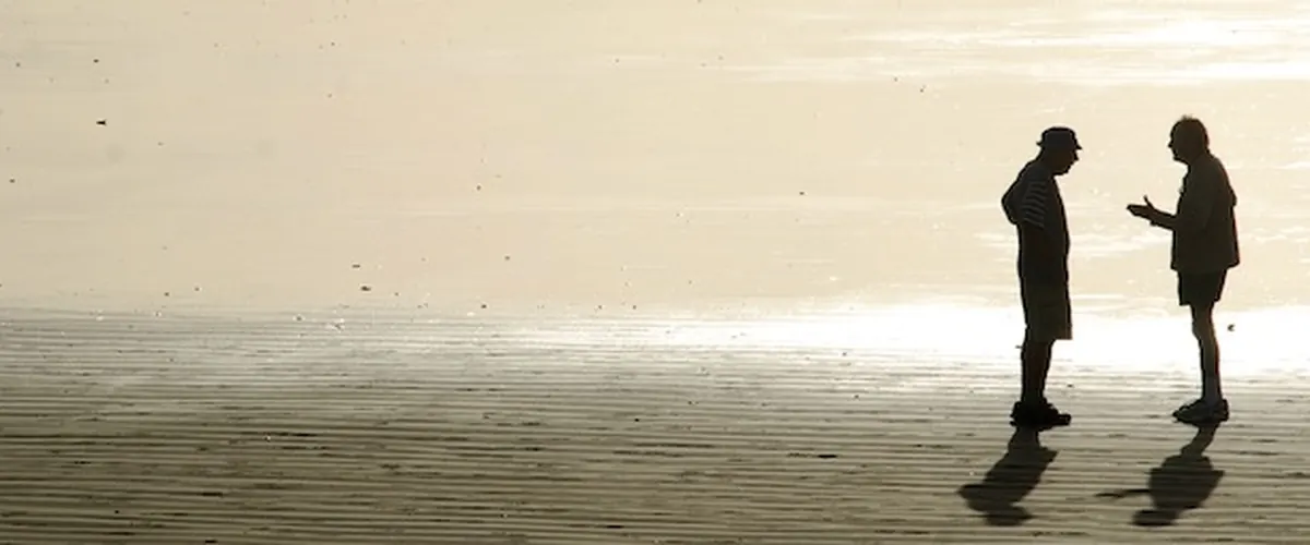 Zwei Menschen im Gespräch am Strand